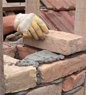 Chimney Repair - Photo of a worker rebuilding a chimney brick by brick.