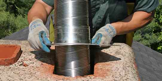 Chimney Liner Installation - Photo of a man replacing a stainless steel chimney liner in a brick chimney.