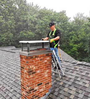 Chimney Repair - Photo of a man repairing a chimney top.