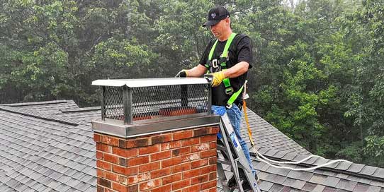Chimney Repair -Photo of a man repairing a chimney top.
