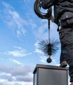 Chimney Sweep Service - Photo of the owner of Riaz Chimney & Masonry getting ready to put a brush type cleaning tool down a chimney.